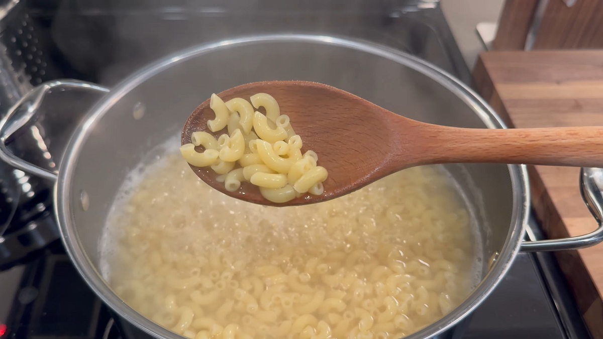 A wooden spoon holding soft, overcooked elbow macaroni