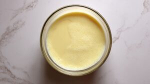 Top view of a bowl with smooth, pale yellow batter being prepared on a countertop