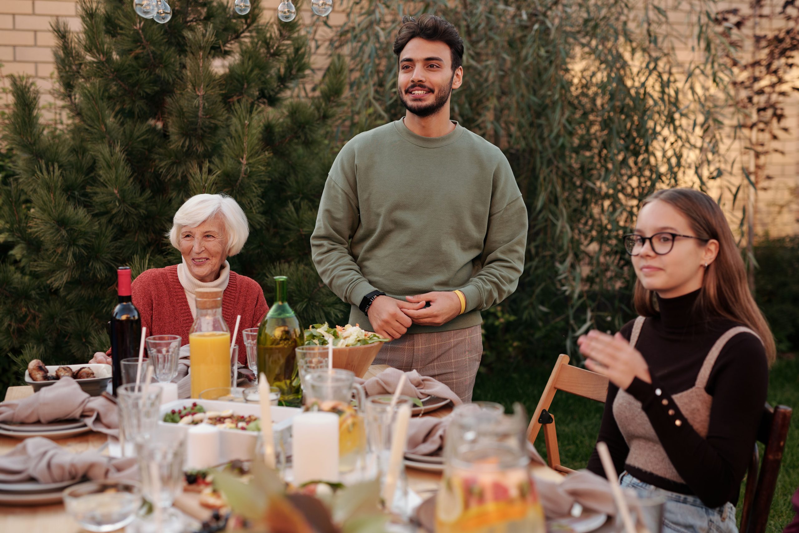 Cheerful family members having dinner party together in a backyard in daytime